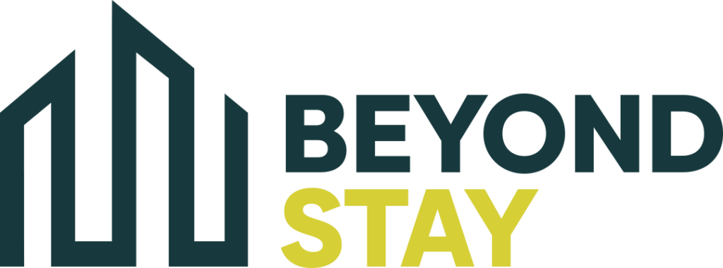 Logo with three stylized dark green building shapes on the left and the words "BEYOND STAY" on the right, highlighting expertise in vacation rentals and property management; "BEYOND" is dark green and "STAY" is yellow.
